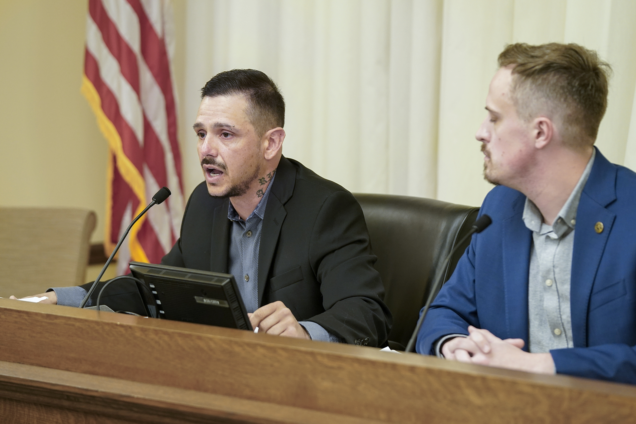 With Rep. Max Rymer, the bill sponsor, looking on, Charles Thayer testifies in support of HF16, a bill to promote sharing of immigration data gathered by state and local entities with federal authorities. His mother was killed by an abusive boyfriend in the country illegally. (Photo by Michele Jokinen)